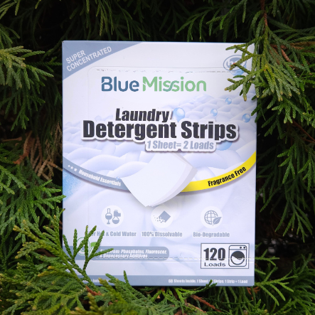 Box of Blue Mission laundry detergent strips on a green leafy background