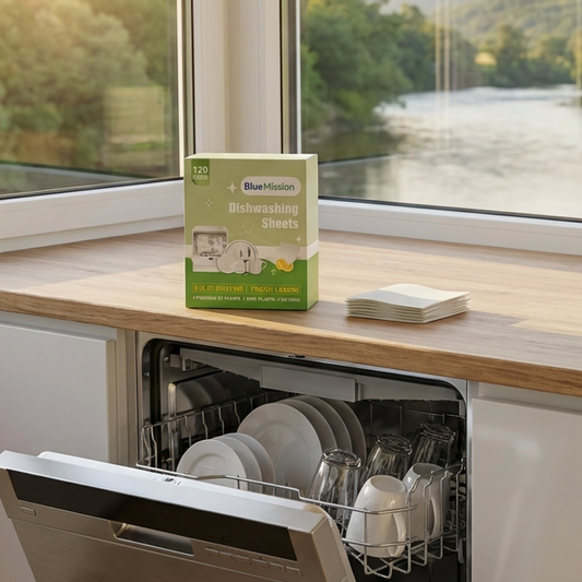 Dishwasher with open door showing clean dishes, box of dishwasher sheets on a window sill with a scenic view.